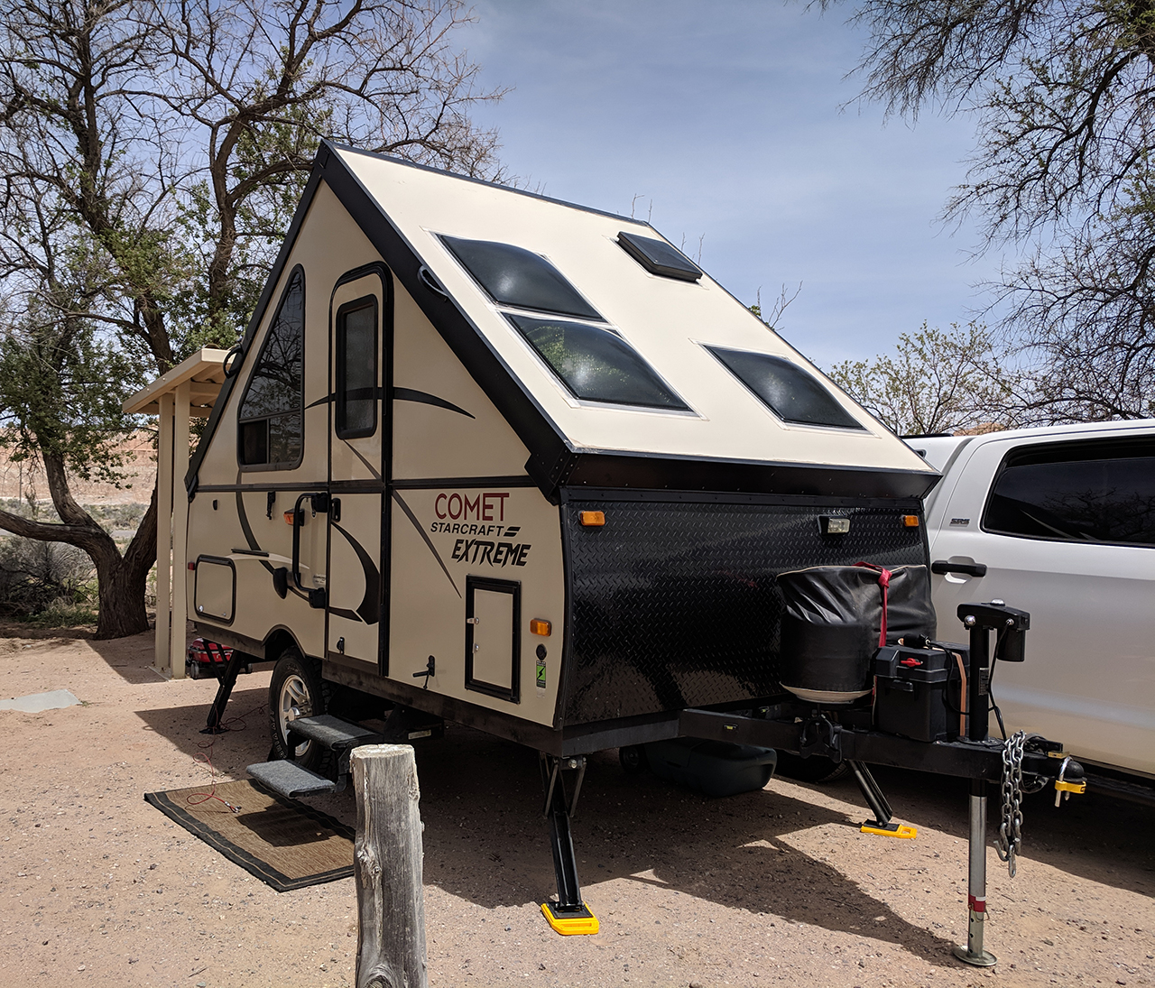 a-frame pop up camper set up in with desert landscaping surround it