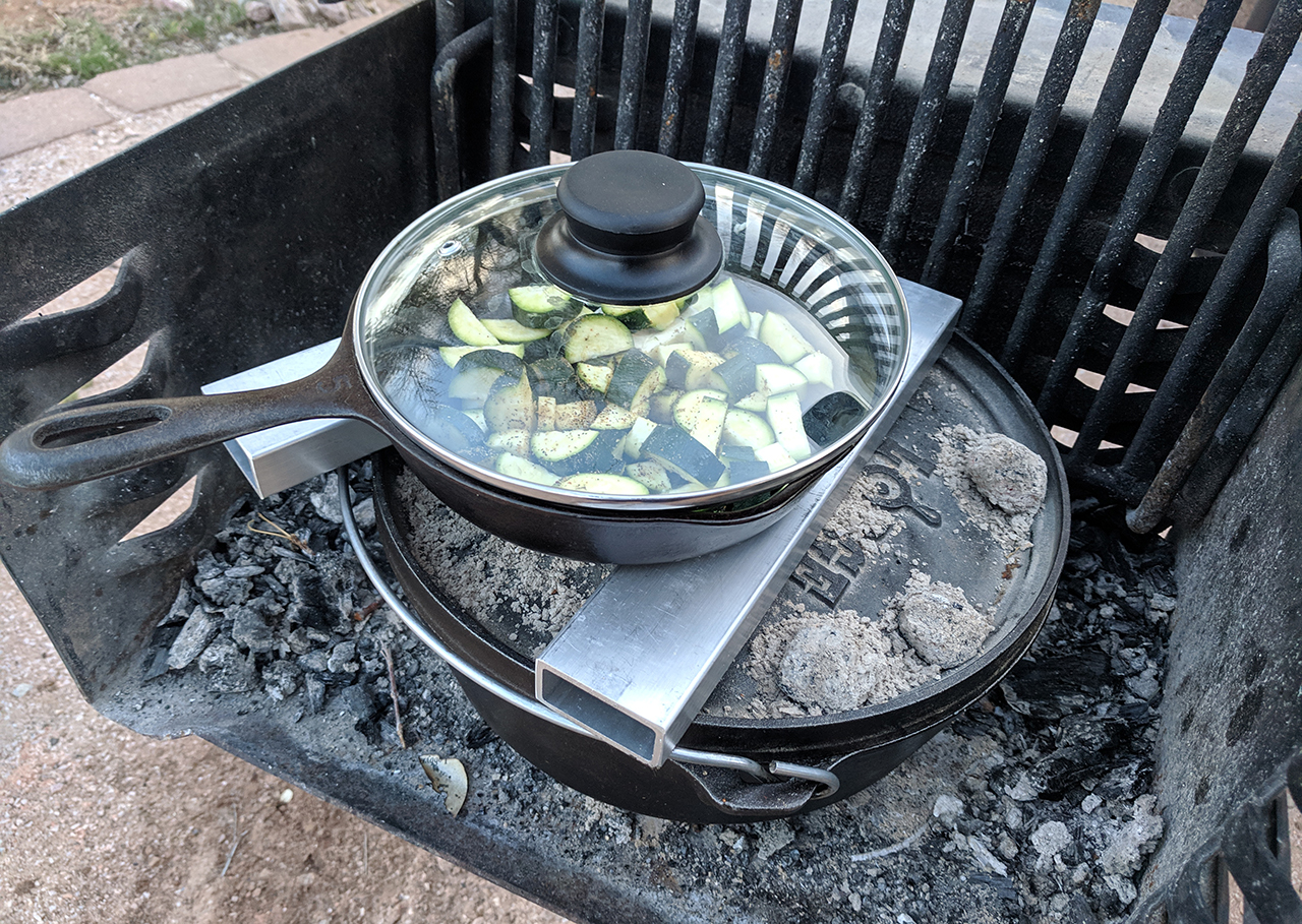 Zucchini in a skillet cooking over top a dutch oven